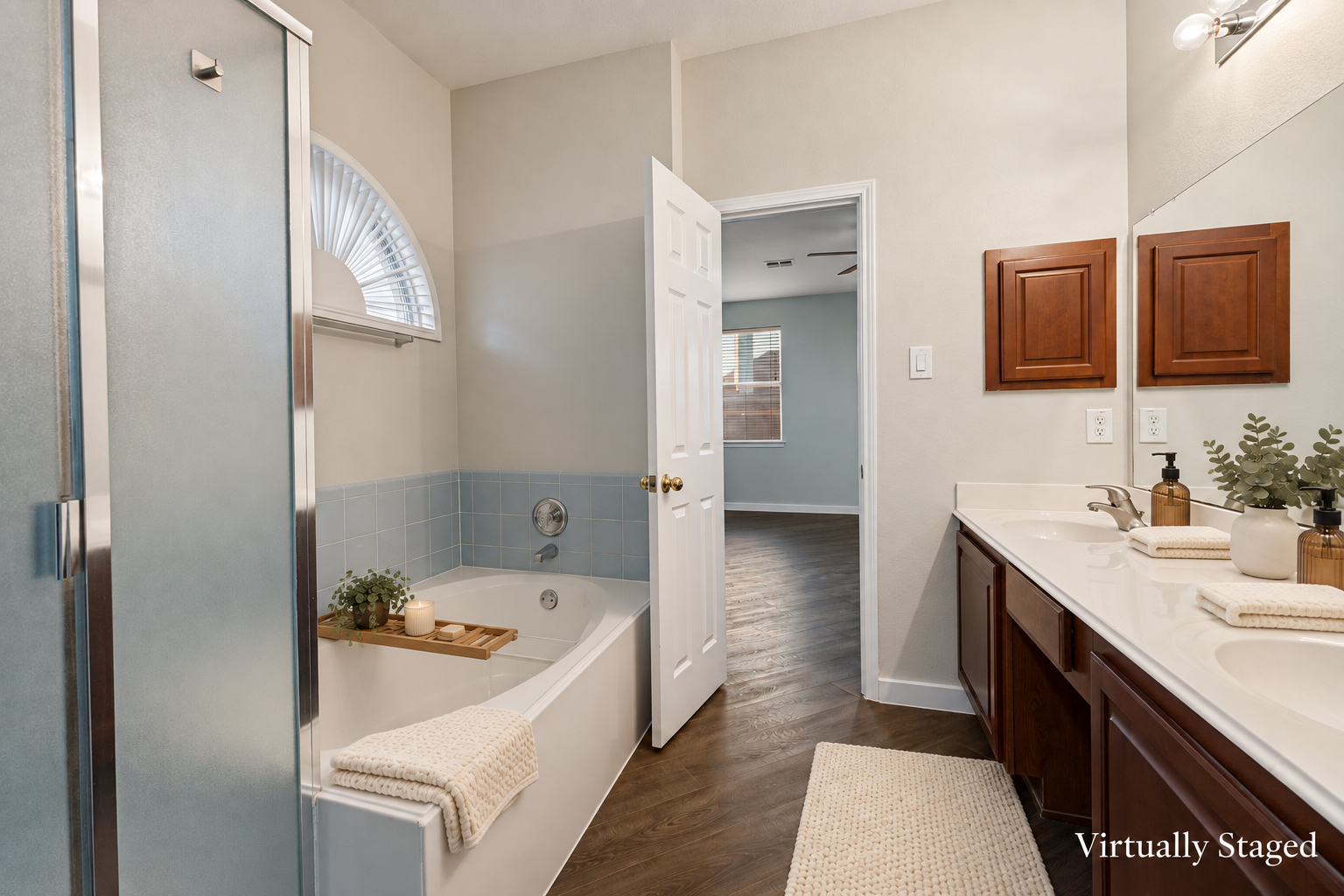 Virtually staged view of the primary suite bath with soaking tub, glass shower, and double vanity at 4215 Maidstone Drive.