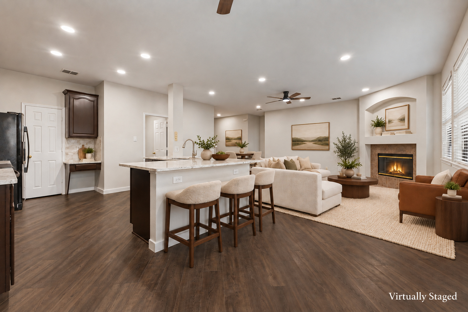 Virtually staged view of the open kitchen island and living area with fireplace at 4215 Maidstone Drive.