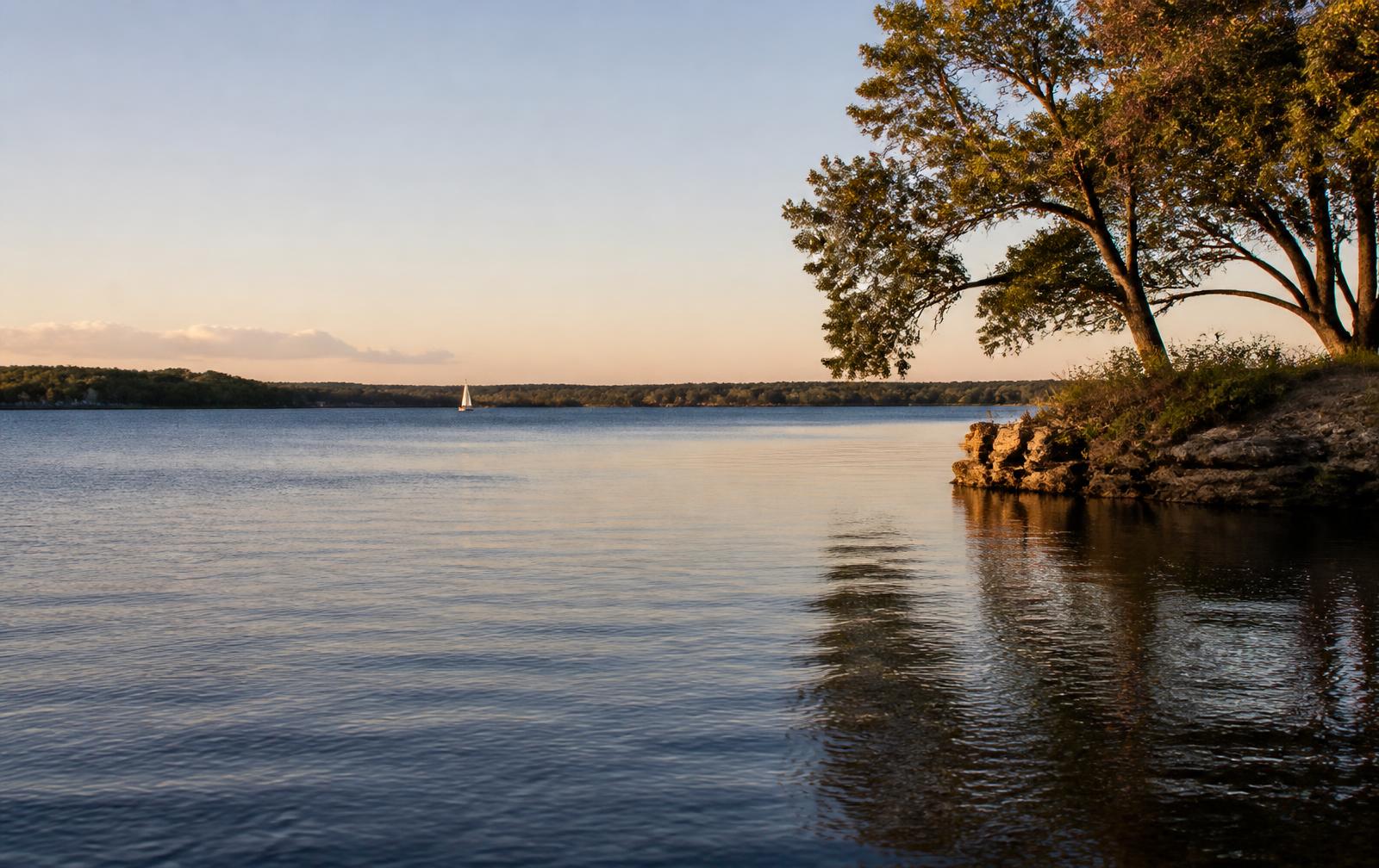 Calm open water and a wooded shoreline at Lake Ray Hubbard at sunset.